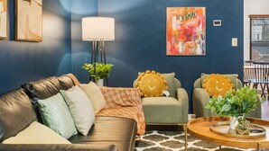 A modern living room with a dark blue accent wall, a sofa, armchairs, a floor lamp, and a painting. - Spacious 4BR Townhouse - Sleeps 13 - Near  DC & Metro (Arlington)