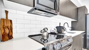 A modern kitchen with a stainless steel range hood, a built-in microwave, and a gas stove. - Bay View Studio | Rooftop Pool, Downtown Miami (Miami)
