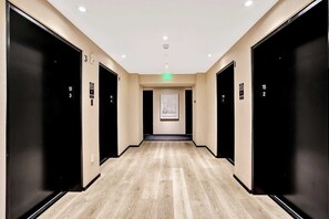 A hotel corridor with black doors numbered 1 to 4, a green exit sign, and a framed picture on the wall. - Bay View Studio | Rooftop Pool, Downtown Miami (Miami)