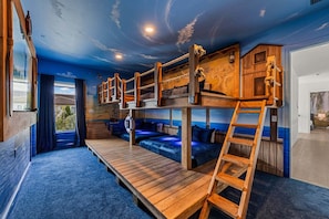 Habitación con literas, una escalera de madera, un banco y vistas al exterior.