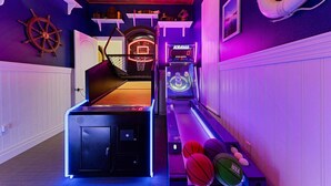 Um quarto com mesa de bilhar, jogos de fliperama e decoração com roda de navio.