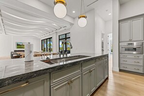 Una cocina moderna con una isla grande, electrodomésticos de acero inoxidable y un comedor con vistas.