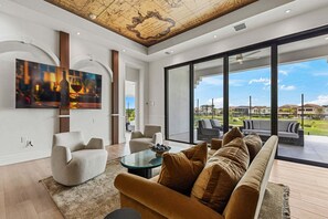 A modern living room with a large window, a sofa, a coffee table, and a painting on the wall. - The Nautilus at Reunion-TT488 (Kissimmee)