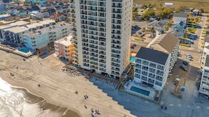 Un hotel moderno con numerosi balconi, una zona piscina e vista sulla spiaggia.