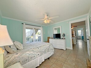 Ein Schlafzimmer mit Bett, Schminktisch, Fernseher und Deckenventilator.