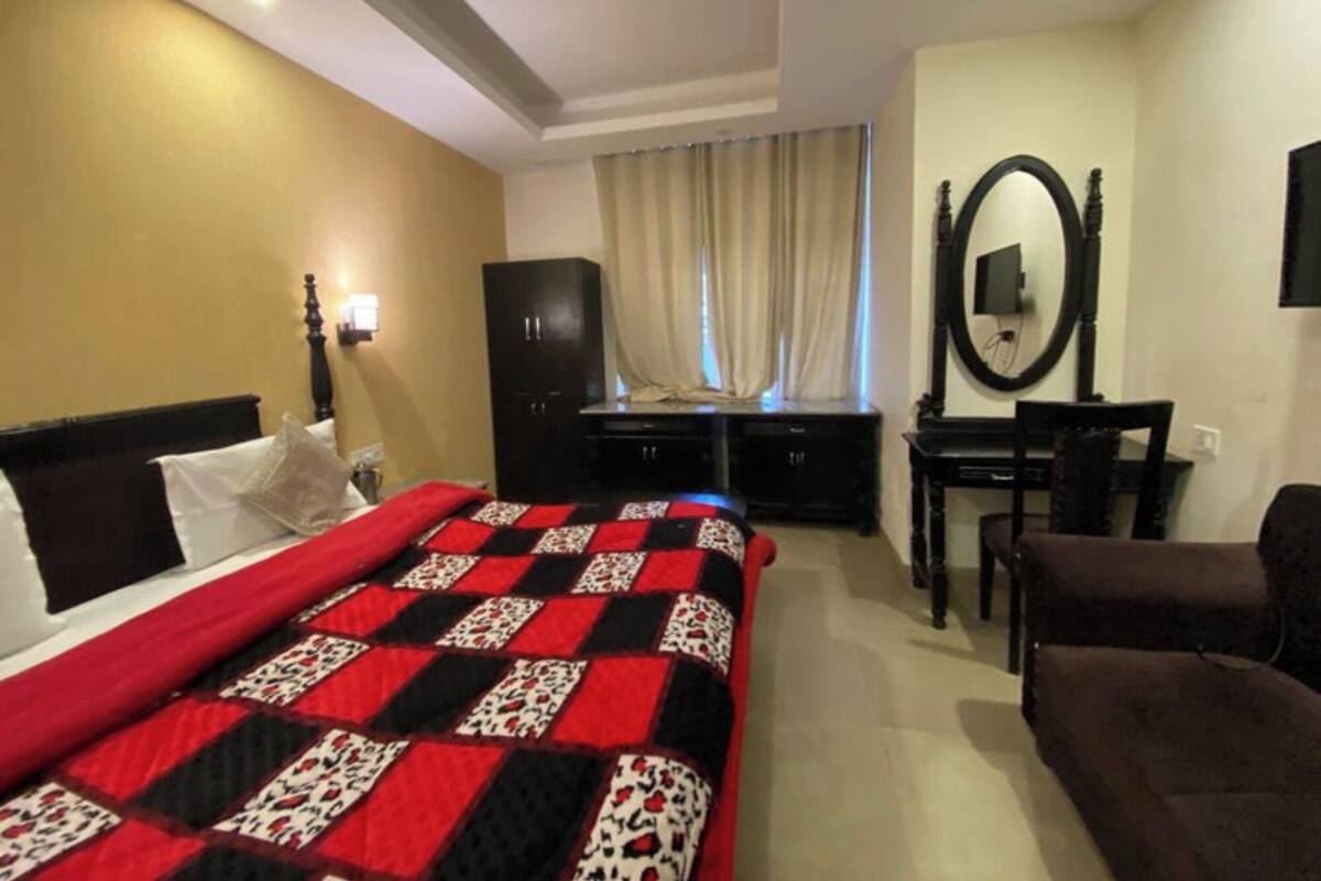 Een hotelkamer met een bed, een bureau, een stoel, een kledingkast en een spiegel.