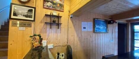 A reception desk with a clock, framed photos, a check-out sign, and a poster on the wall.