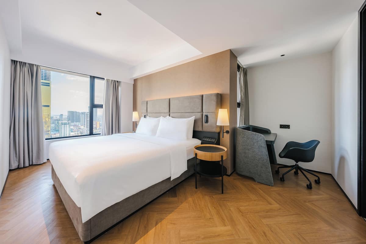 Ein modernes Hotelzimmer mit einem großen Bett, einem Schreibtisch und einem Sessel.