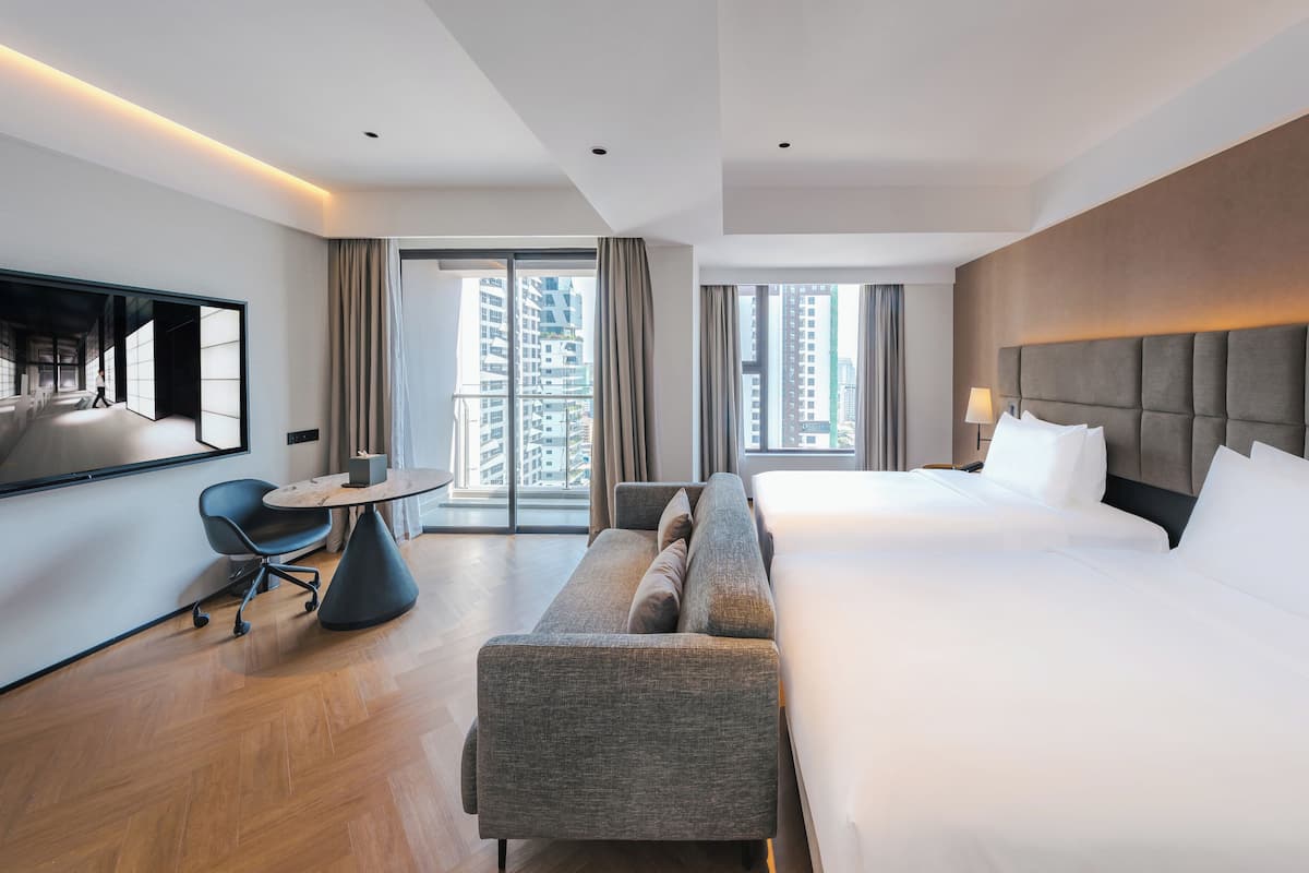 Ein modernes Hotelzimmer mit einem großen Bett, einer Couch, einem Schreibtisch und einem Fernseher.