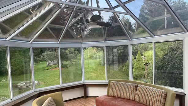 A conservatory with a glass ceiling, a cushioned bench, and a view of a garden. - Delightful 4-bedroom house in Windham. 1 mile to Windham resort & walk to town. (Windham)