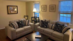 A living room with two sofas, a coffee table, a lamp, and framed artwork on the walls. - Delightful 4-bedroom house in Windham. 1 mile to Windham resort & walk to town. (Windham)