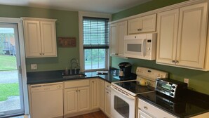 A kitchen with white cabinets, a black countertop, a microwave, a toaster, and a window with blinds. - Delightful 4-bedroom house in Windham. 1 mile to Windham resort & walk to town. (Windham)