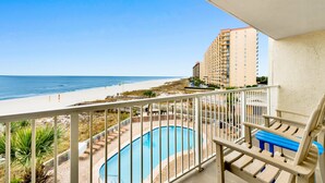 Uma varanda com piscina, com vista para uma praia e oceano.