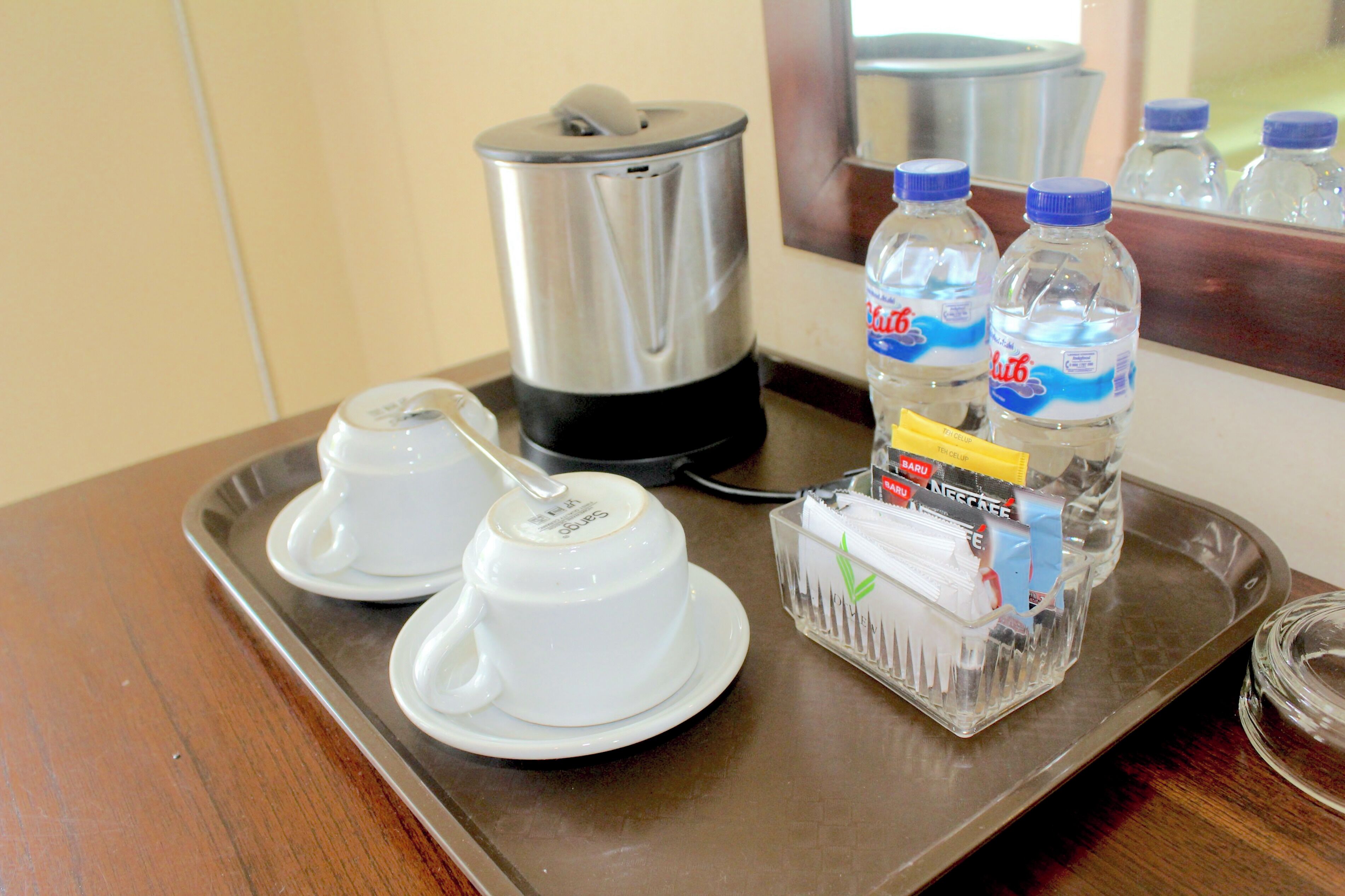 A tray with a coffee maker, two white cups, and a water bottle.
