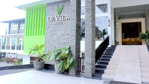 The exterior of the Devview Hotel with a modern design, featuring a prominent sign, large potted plants, and a staircase leading to the entrance. - De View Hotel Batu (Batu)