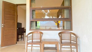 A room with a wooden door, a window with curtains, and two wooden chairs and a small table. - De View Hotel Batu (Batu)