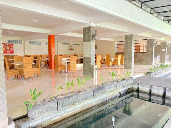 A spacious indoor area with multiple seating arrangements, a central water feature, and a modern architectural design.