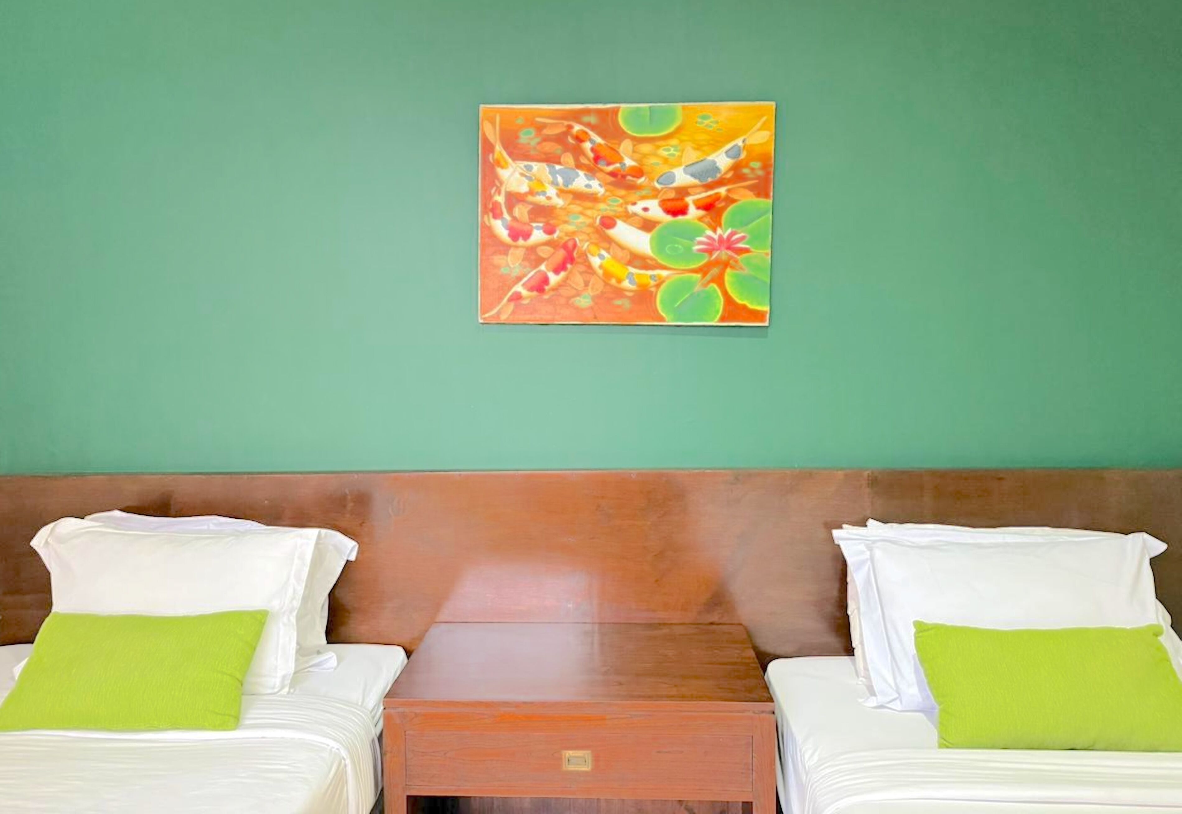 Une chambre avec deux lits, une tête de lit en bois et un tableau au mur.