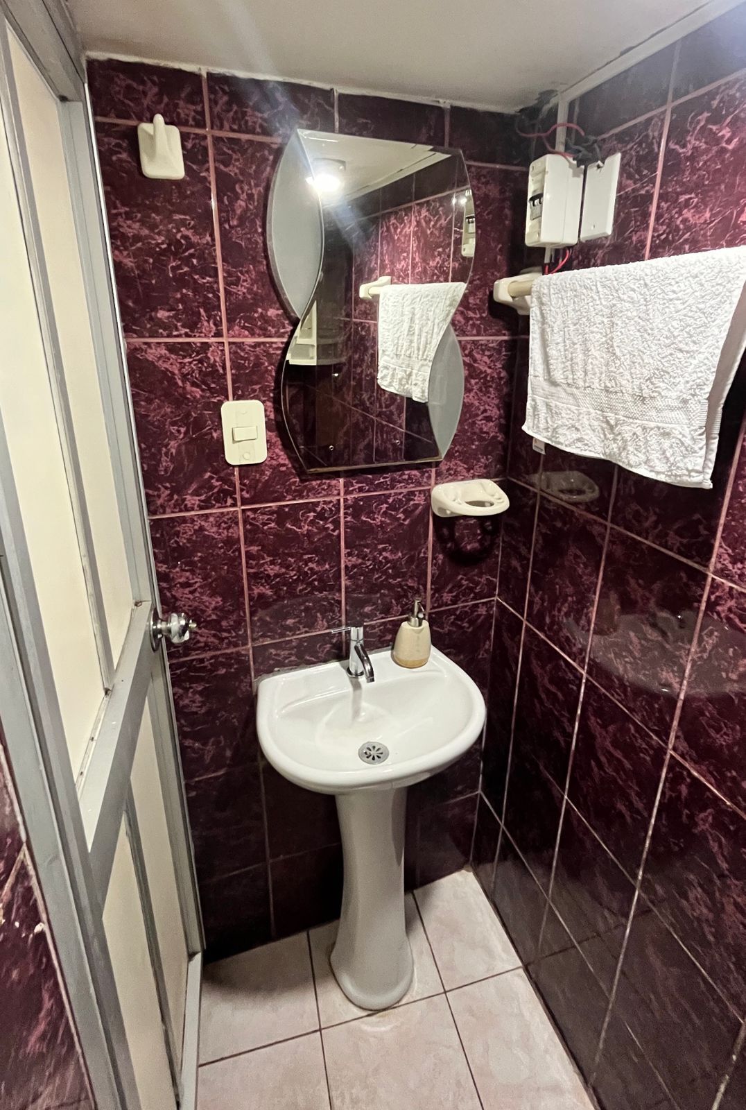 A bathroom with a pedestal sink, a mirror, a towel rack, and a toilet.