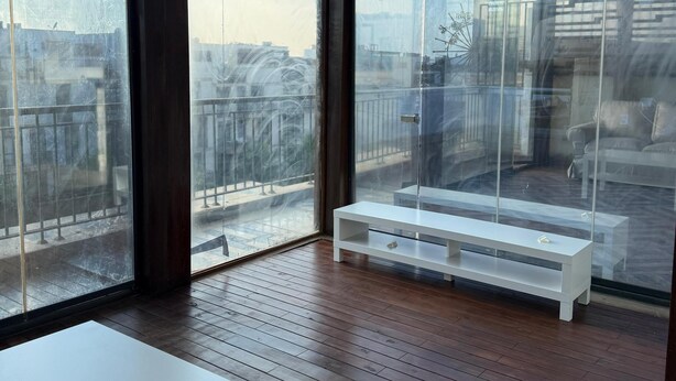 A modern room with large windows, a white bench, and a white table. - ALSAWAH Modern Rooftop with Private Terrace Sheikh Zayed (Sheikh Zayed City)