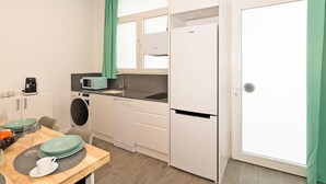 Une cuisine compacte équipée d’un lave-linge, d’un four à micro-ondes et d’un réfrigérateur.