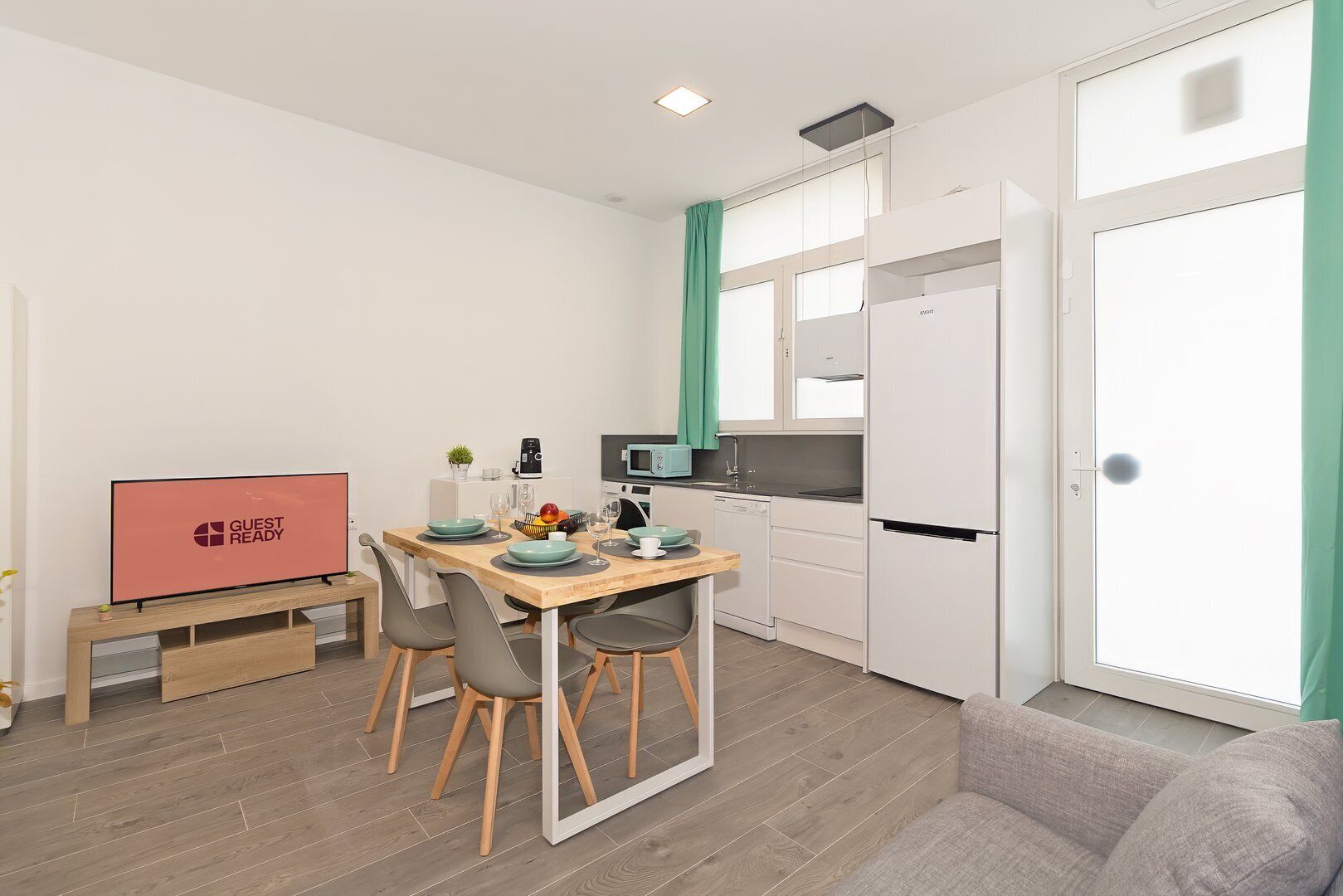 Un espacio habitable compacto con comedor, kitchenette y televisor.