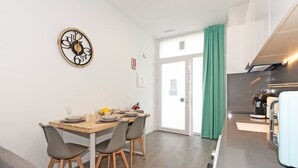 Een moderne keuken met een eethoek, een koffieapparaat en een groot raam met gordijnen.