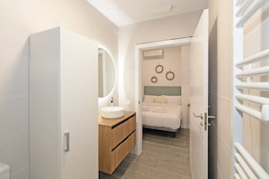 A modern bathroom with a round sink, wooden vanity, and a bed with a headboard. - GuestReady - Modern studio in Valencia ’s new area (Valencia)