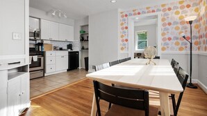 A modern kitchen with white cabinets, a dining table with chairs, and a patterned wallpaper. - Contemporary City Getaway  Luxe Comfort (Arlington)