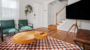 A living room with a green sofa, a wooden coffee table, and a TV on a stand. - Contemporary City Getaway  Luxe Comfort (Arlington)