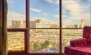 A room with a large window offering a view of a city skyline, including a Ferris wheel and various buildings.