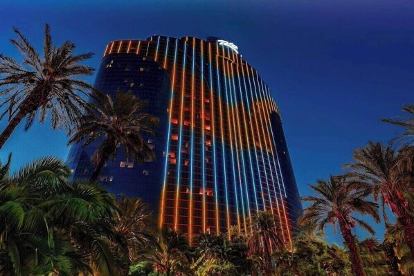 A tall, modern building with a distinctive vertical lighting pattern and a visible logo at the top.