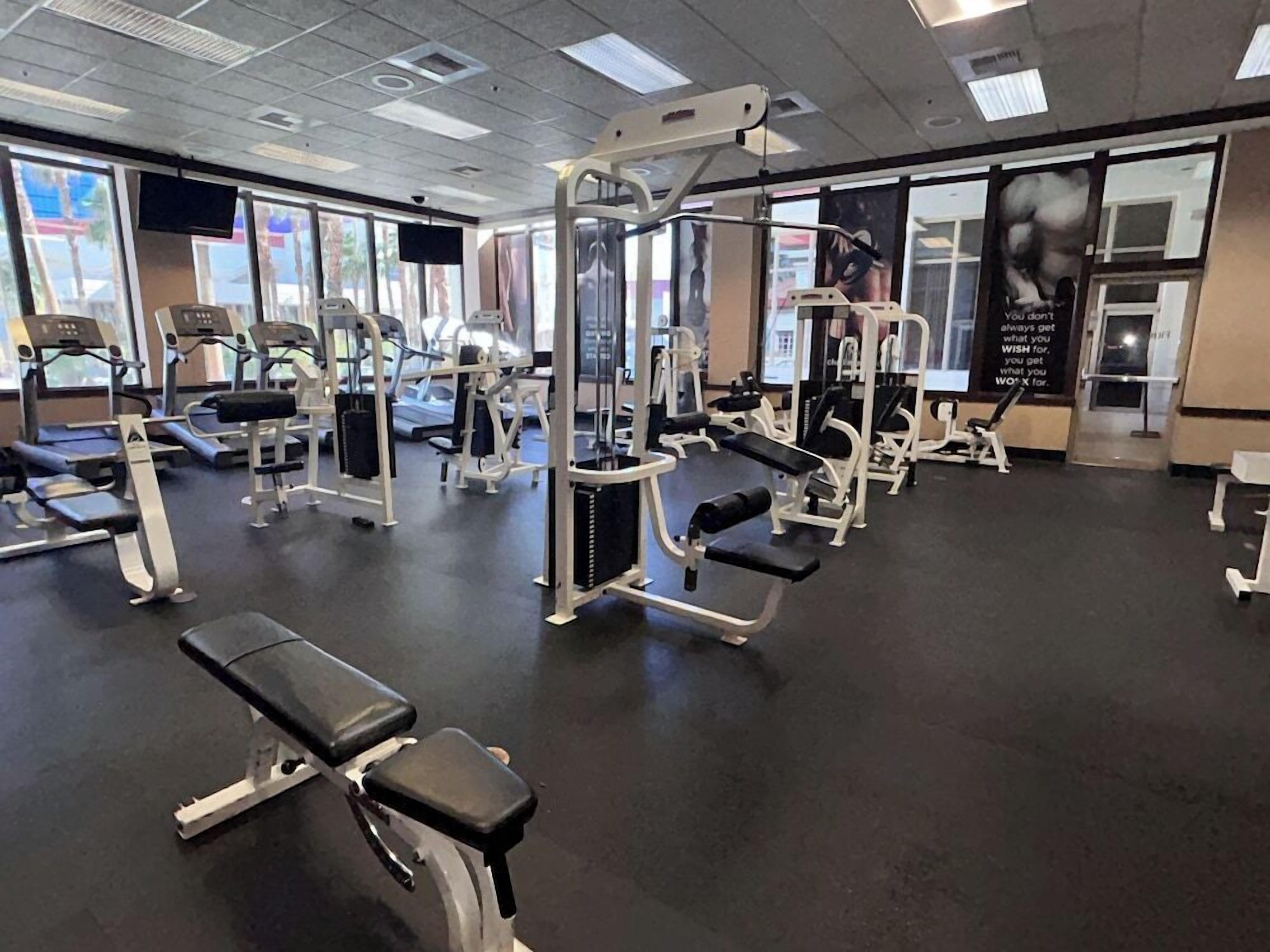 A gym with various exercise equipment, including treadmills, weight machines, and benches.