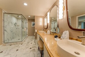 Een moderne badkamer met een douchecabine van glas, een marmeren vloer, een wastafelmeubel met een wastafel en grote spiegels met ingebouwde verlichting.