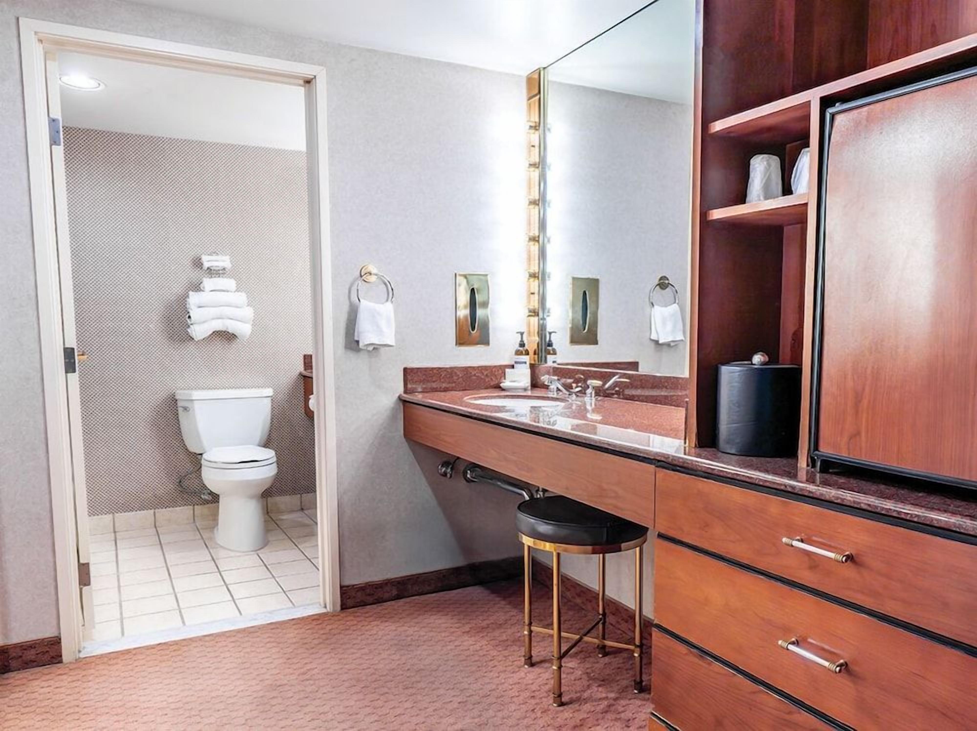 A bathroom with a toilet, sink, mirror, and towel rack.