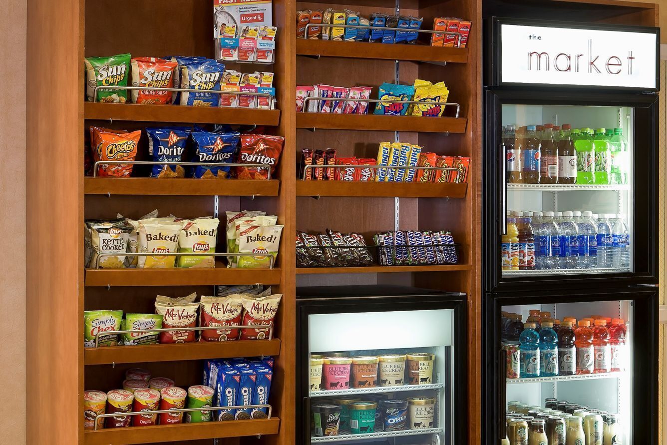 Exhibición de aperitivos y bebidas en una tienda, con papas fritas, galletas y refrescos variados.