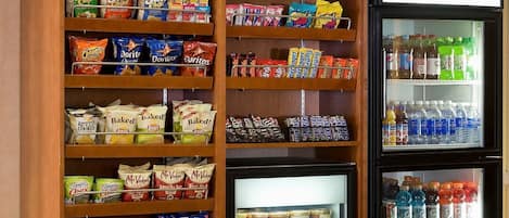 Exhibición de aperitivos y bebidas en una tienda, con papas fritas, galletas y refrescos variados.