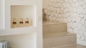 A staircase with a textured wall, a blue vase, and three bottles on a shelf. - Villa Maiora Tres Bingin (Pecatu)