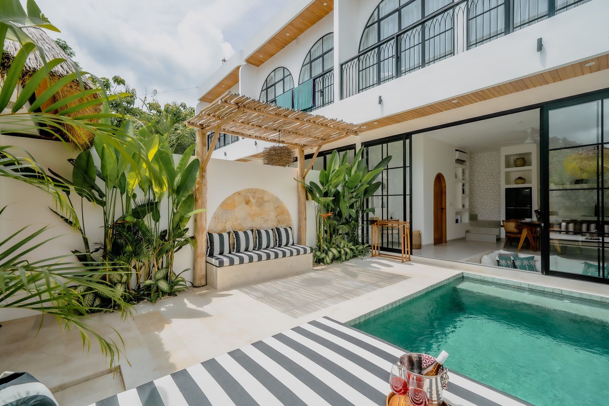 A modern house with a pool, outdoor seating, and lush greenery.