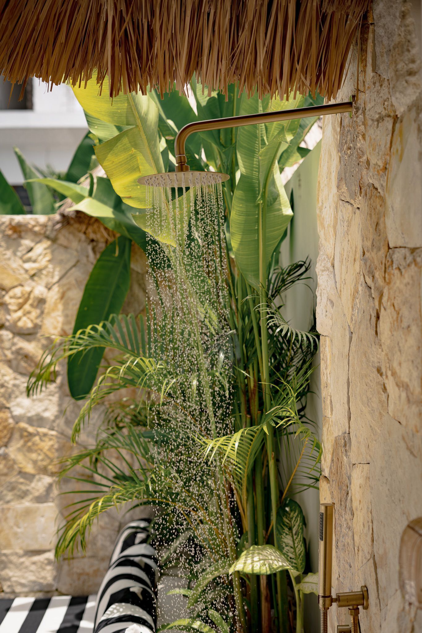 A shower with a thatched roof, surrounded by lush tropical plants.