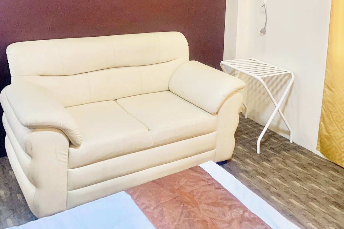 Un sofá beige en una habitación con una pequeña mesa blanca y una alfombra estampada.