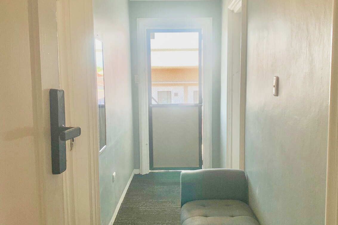 A narrow hallway with a door on the left and a window at the end.