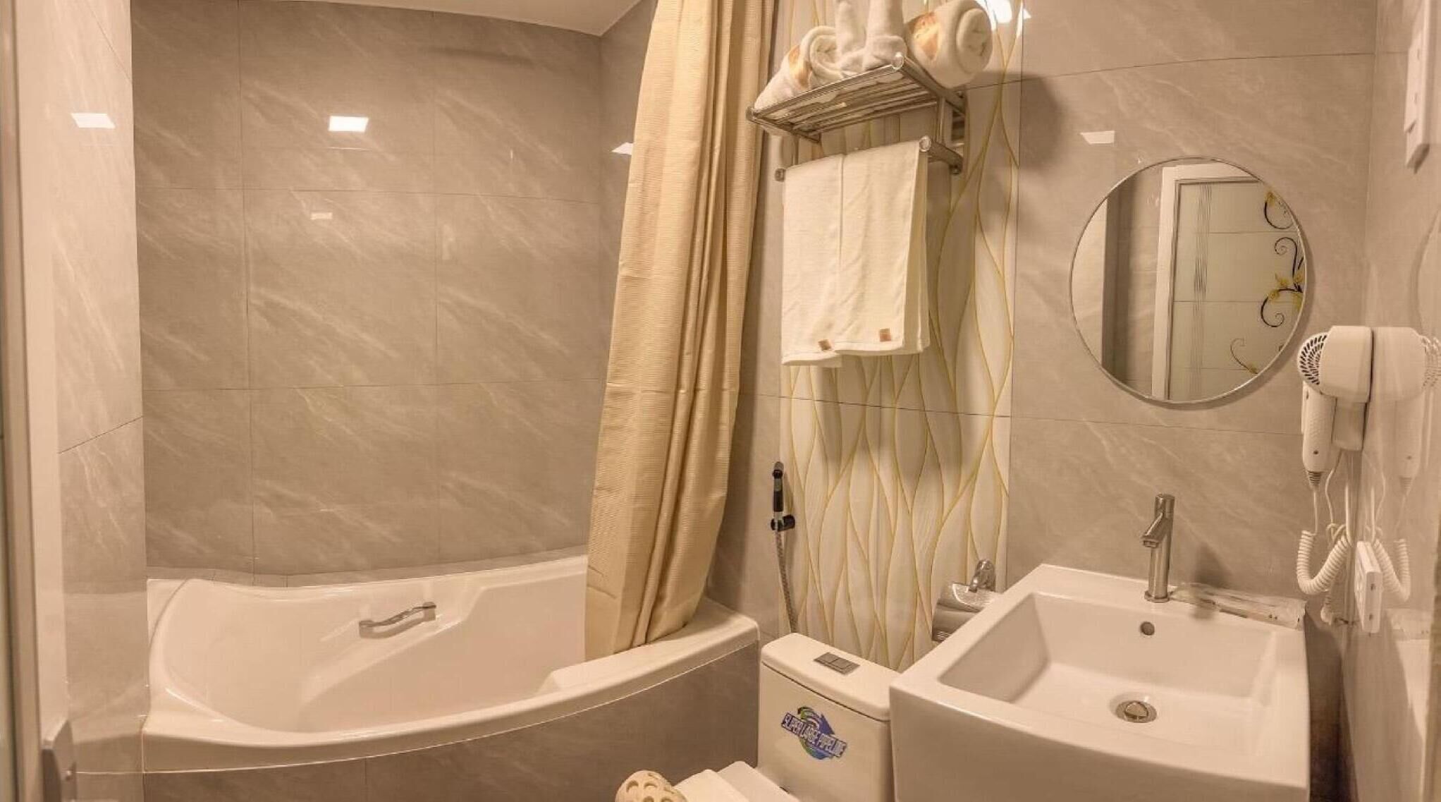 Un baño con bañera, lavamanos, espejo y secador de pelo.