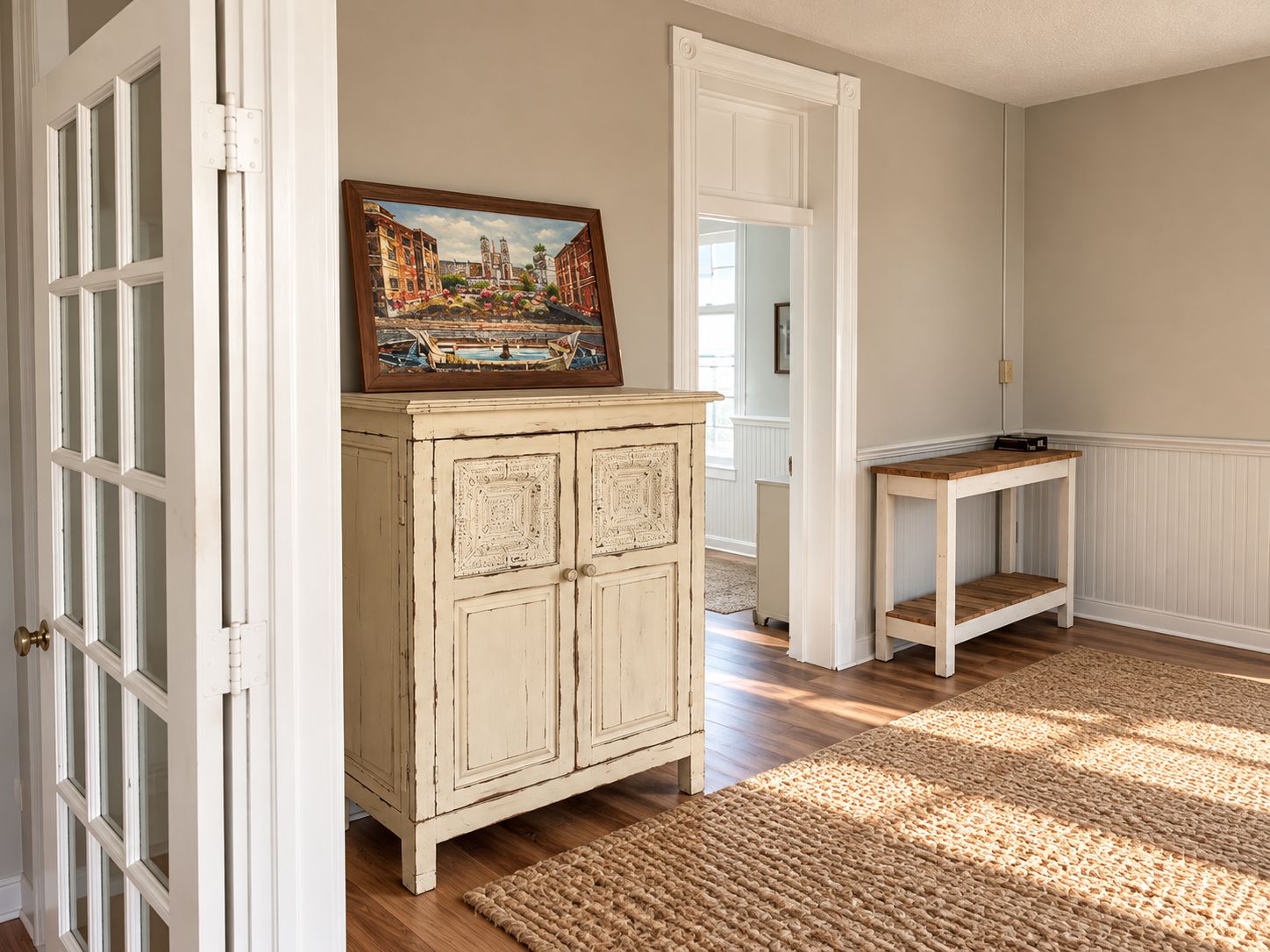 A hallway with a wooden cabinet, a painting, and a small table.