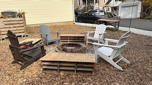 Un cortile con poltrone Adirondack, un braciere e un tavolo in legno.