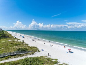 Ein Strand mit sandigem Ufer, einer Holzpromenade und blauem Himmel.