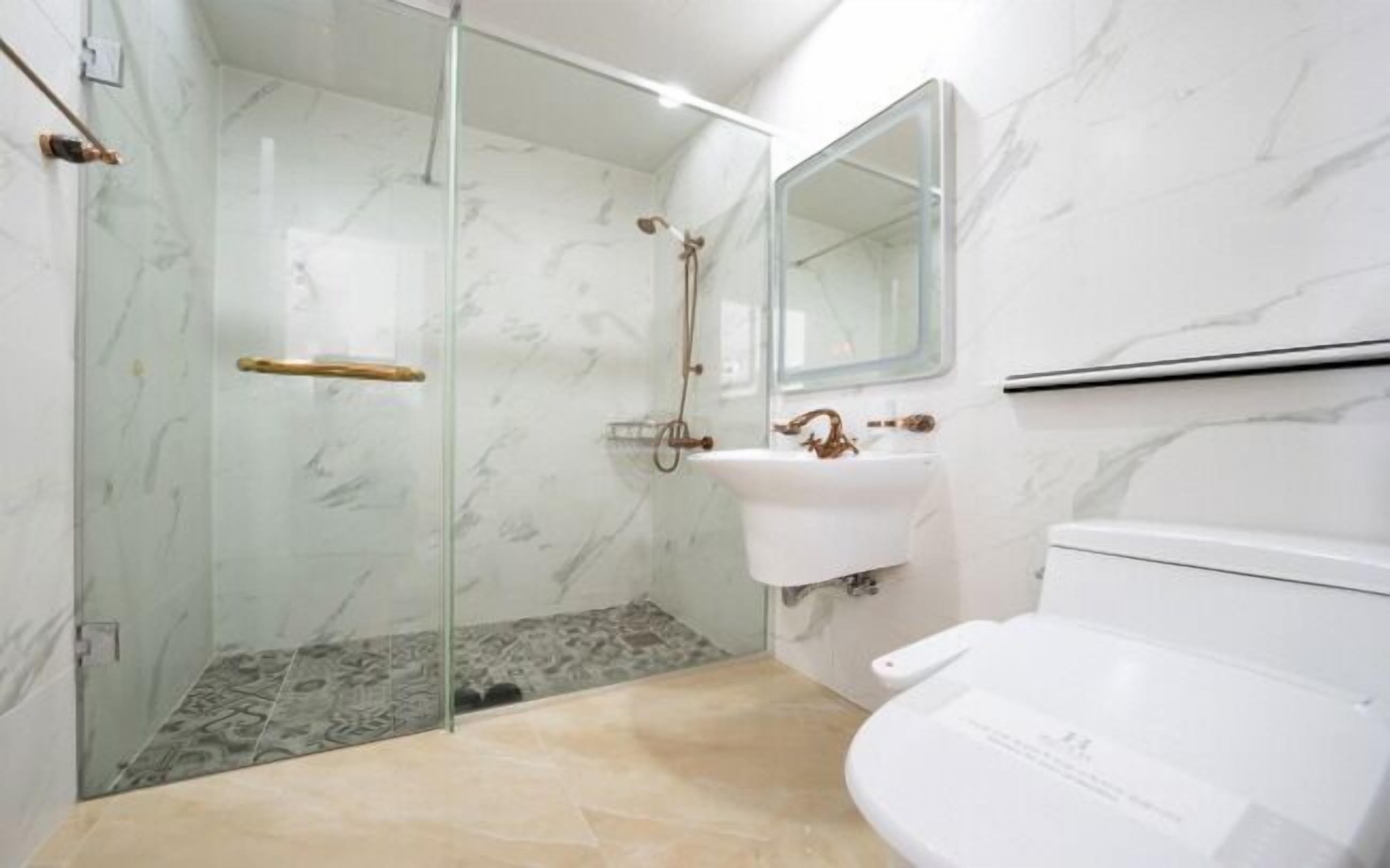 Un baño con ducha envuelta en vidrio, un lavabo blanco y un inodoro.