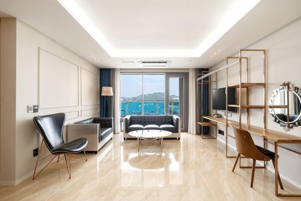 A modern hotel room with a balcony, a sofa, a coffee table, and a TV.