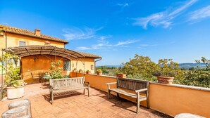 Una terraza con un banco de madera, una mesa y plantas en macetas.