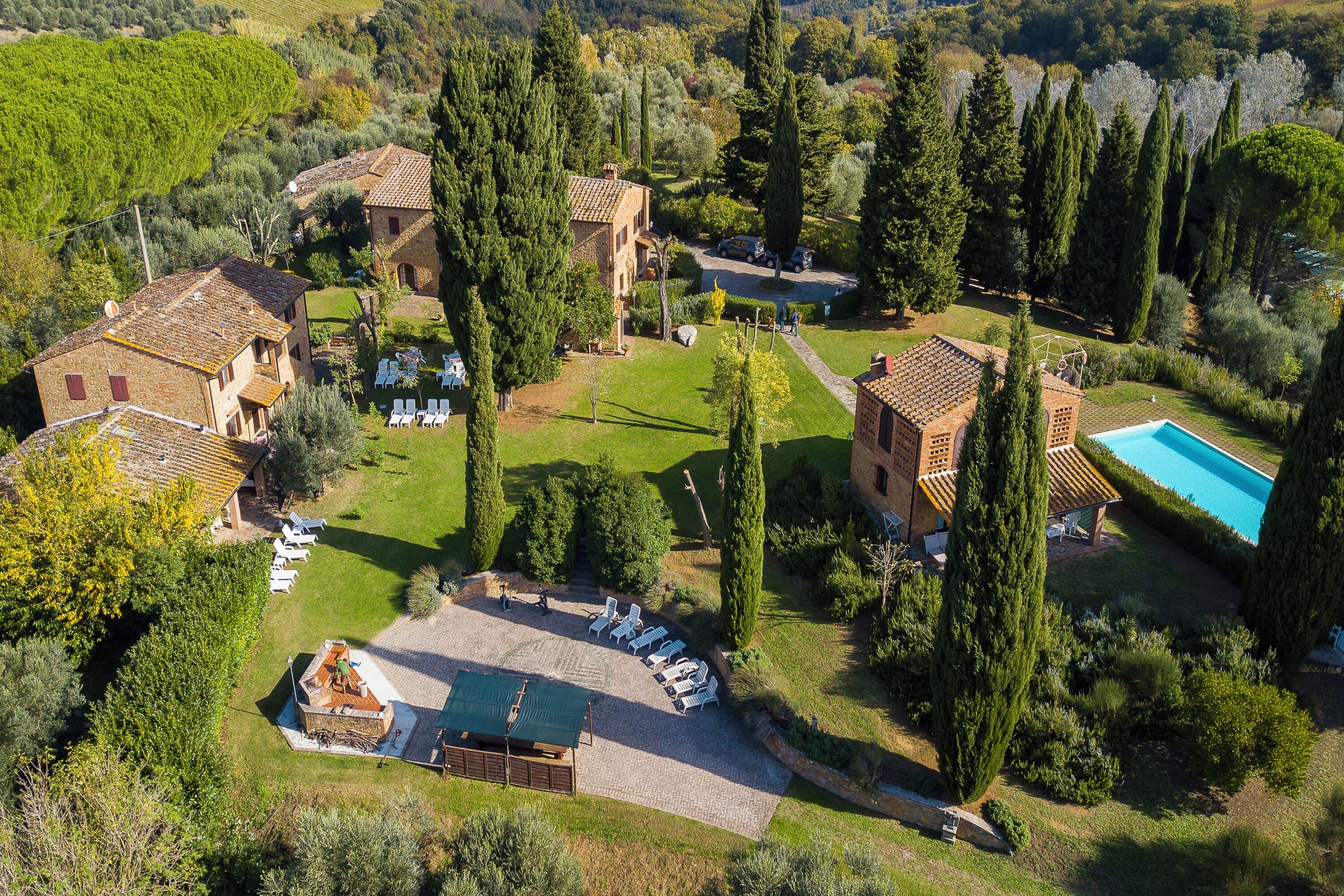 An aerial view of a property with multiple buildings, a swimming pool, and outdoor seating areas.